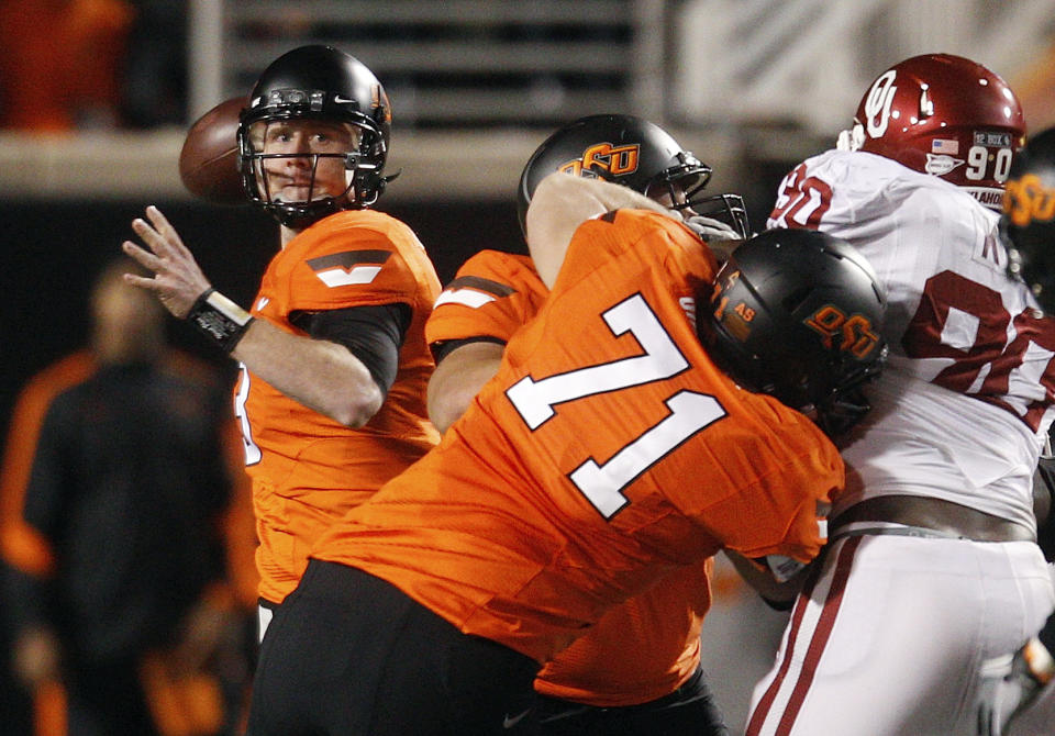 FILE - Oklahoma State quarterback Brandon Weeden, left, looks to pass against Oklahoma in the third quarter of an NCAA college football game in Stillwater, Okla., Dec. 3, 2011. Oklahoma and Oklahoma State will meet on Saturday for the final time before Oklahoma leaves the Big 12 for the Southeastern Conference. (AP Photo/Sue Ogrocki, File)