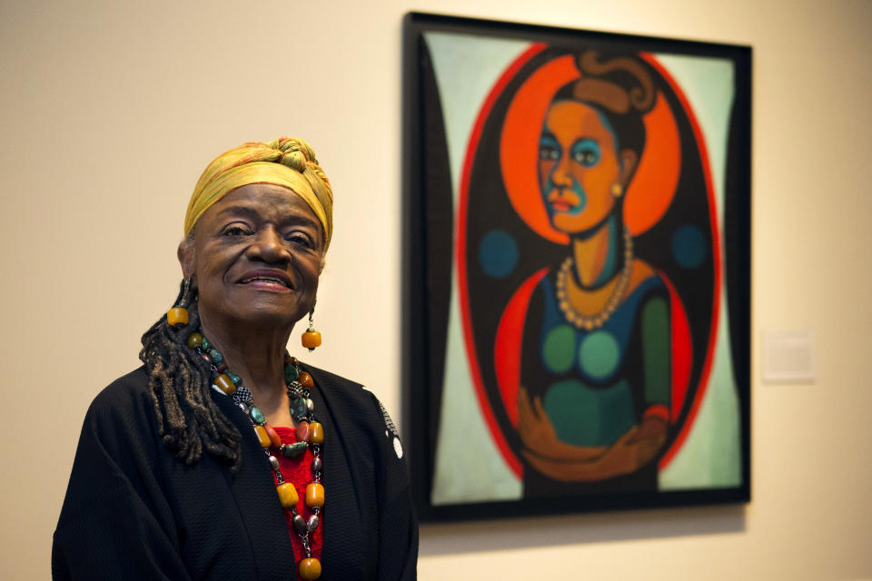 FILE - Artist Faith Ringgold poses for a portrait in front of a painted self-portrait during a press preview of her exhibition, "American People, Black Light: Faith Ringgold's Paintings of the 1960s" at the National Museum of Women in the Arts in Washington, June 19, 2013. Ringgold, an award-winning author and artist who broke down barriers for Black female artists and became famous for her richly colored and detailed quilts combining painting, textiles and storytelling, died Friday, April 12, 2024, at her home in Englewood, N.J. She was 93. (AP Photo/Jacquelyn Martin, File)