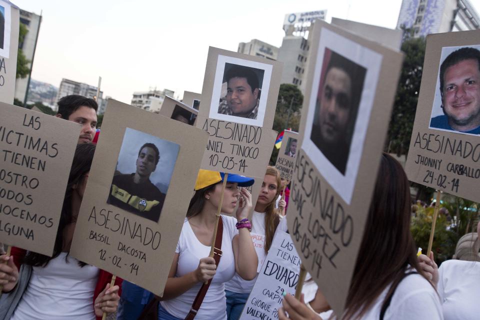 Anti-government demonstrators holds cardboard posters showing images the demonstrator killed during protests, inside Plaza Altamira in Caracas, Venezuela, Tuesday, March 18, 2014. The posters have the the date of death, the name of a dead demonstrator and the word "Assasinated" written in Spanish. Protesters blocked the streets only when traffic lights turned red under the watchful gaze of the National Guard. Security forces have taken control of the plaza that has been at the heart of anti-government protests that have shaken Venezuela for a month. (AP Photo/Esteban Felix)