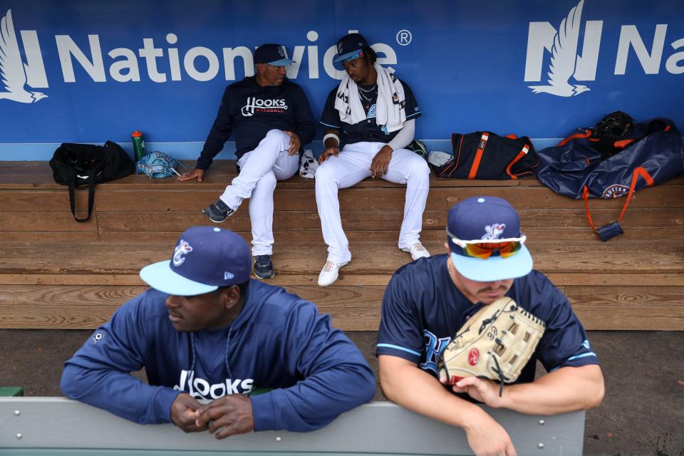 Hooks hitting coach Bobby Bell, back left, speaks to Zach Daniels, right, in the dugout before the exhibition game against Texas A&M-Kingsville at Whataburger Field on April 4, 2023, in Corpus Christi, Texas.