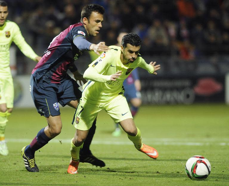 Huesca's Carlos David Moreno (L) challenges Barcelona's Pedro Rodriguez during the the match at El Alcoraz stadium in Huesca on December 3, 2014