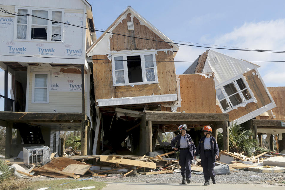 Emergency workers Dr. Patricia Cantrell, left, and Ana Kaufmann, with the South Florida Search and Rescue Task Force 2, survey damage at the western edge of town in Mexico Beach, Fla., after Hurricane Michael swept through the area Thursday, Oct. 11, 2018. (Douglas R. Clifford/Tampa Bay Times via AP)