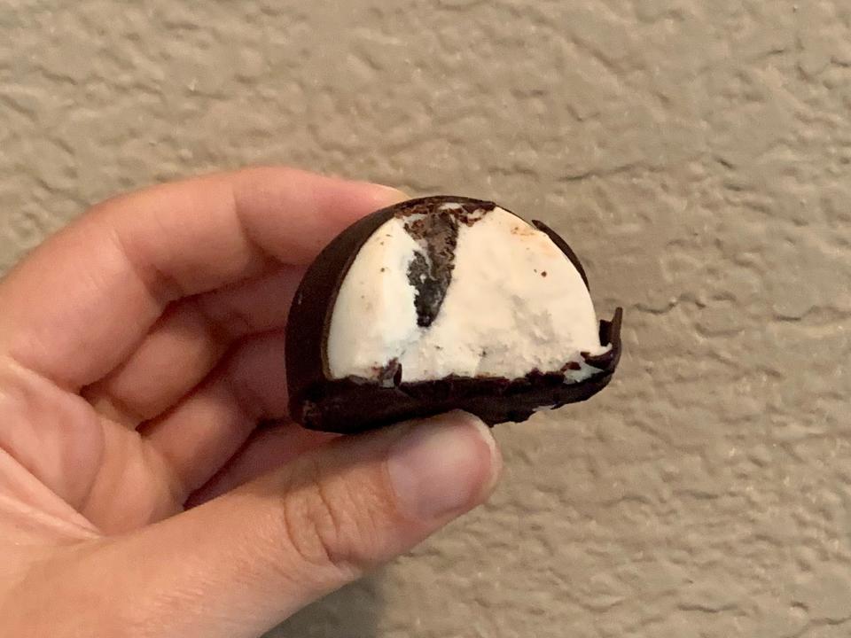 hand holding trader joe's cookies and cream vegan bonbon that's half eaten