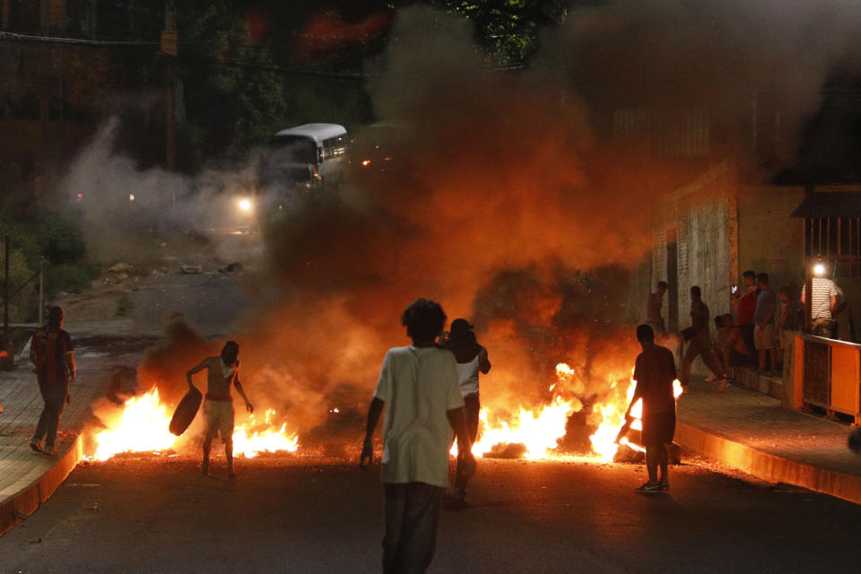 Manifestantes incendian neumáticos para impedir el tráfico en una calle durante una protesta para exigir la renuncia del presidente Juan Orlando Hernández, en Tegucigalpa, Honduras, la noche del viernes 18 de octubre de 2019. (AP Foto/Elmer Martínez)