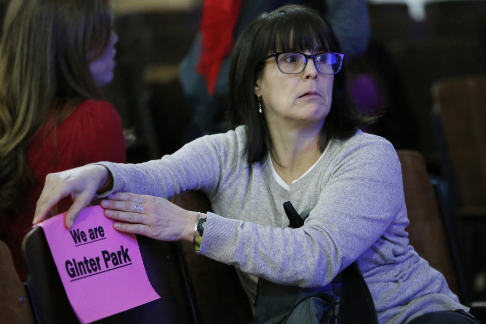 In this Dec. 16, 2019, photo, Ginter Park Elementary School teacher Robin Keegan attaches a sign to a chair during the Richmond School Board's last public hearing on redistricting in Richmond, Va. In Virginia’s capital city, the school board approved a plan that reassigned some students but rejected more sweeping proposals that would have diversified Richmond’s whitest elementary schools. (AP Photo/Steve Helber)