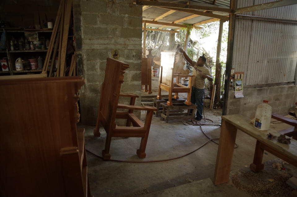 A worker sprays a wooden chair that will be used by Cardinals and Bishops during Pope Francis' Mass at the Metropolitan Cathedral on World Youths Day, at Hernan Guardia's carpentry workshop where the Pope's chair is also being built in Los Pozos, Panama, Saturday, Jan. 12, 2019. The Argentine pontiff visit Panama Jan. 23-27. (AP Photo/Arnulfo Franco)