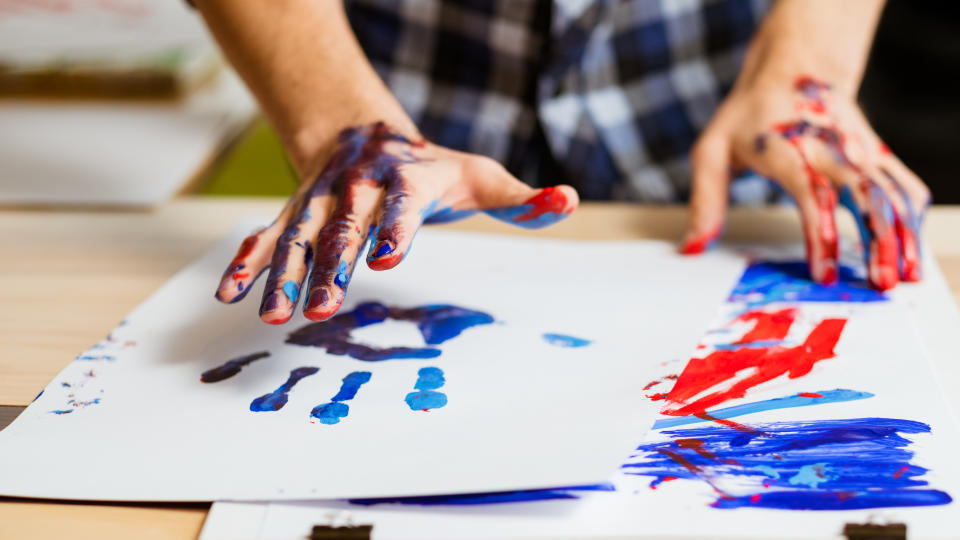 Art therapy class school. Colorful man hand print on white paper. Artist hands smeared with paint. Hobby education.