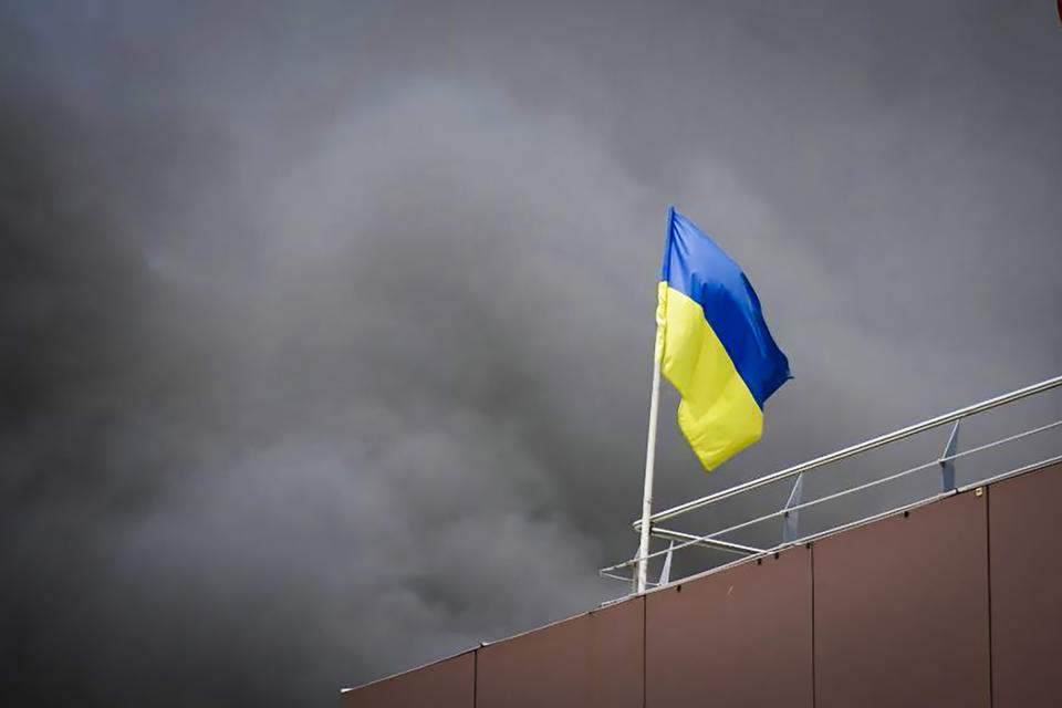 In this photo released by the Dnipro Regional Administration, Ukrainian flag waves as smoke rises after Russia's missile attack in Dnipro, Ukraine, Wednesday, July 3, 2024. (Dnipro Regional Administration via AP)