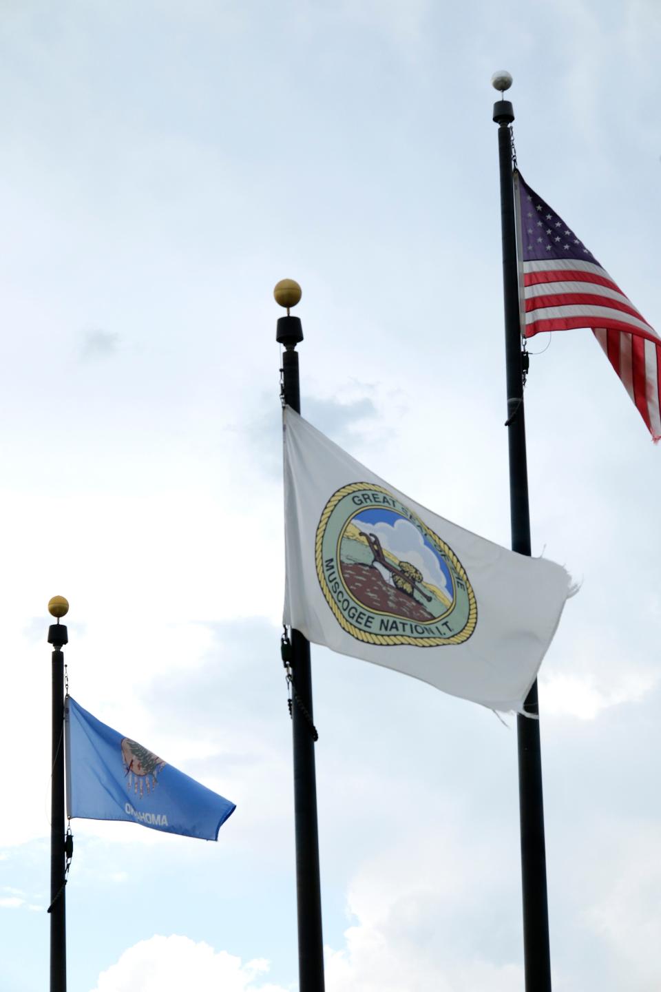 Oklahoma, Muscogee Nation and American flags fly in the wind.