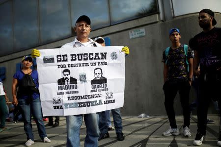 An opposition supporter holds a placard that reads "Wanted for destroy a country. Reward: A free Venezuela" with images depicting Venezuela's President Nicolas Maduro (L) and Diosdado Cabello, deputy of Venezuela's United Socialist Party (PSUV), during a rally to demand a referendum to remove Maduro in Caracas, Venezuela September 1, 2016. REUTERS/Marco Bello