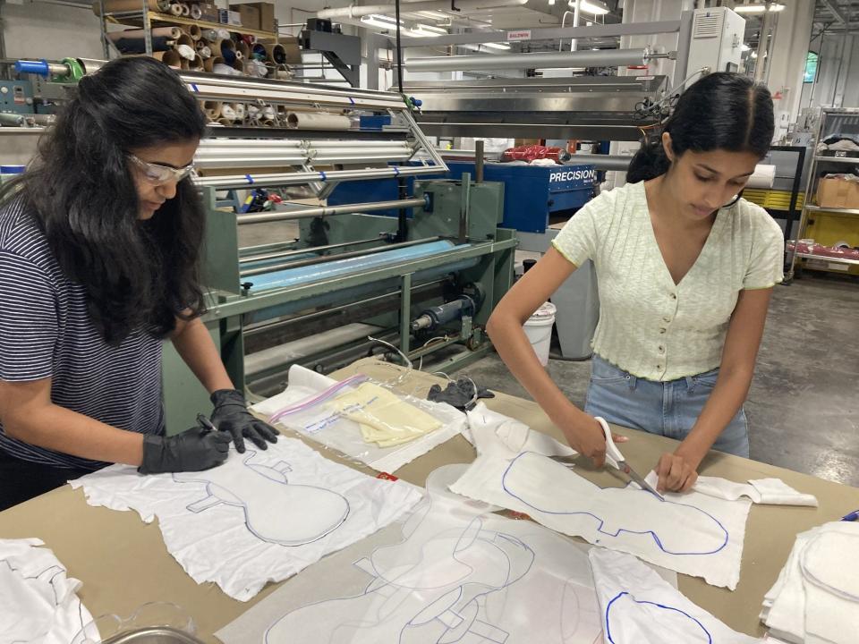 Nandini Kanthi, left, and Anisha Roy work on fabric for the Sensible pad prototype at the NC State textiles lab.