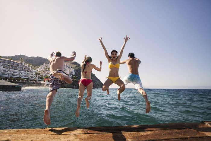 Group of friends jumping into the ocean water