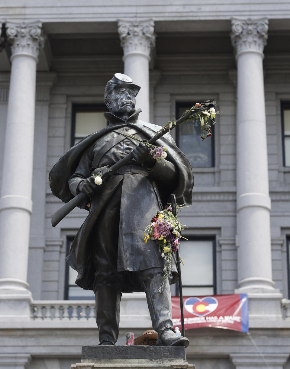 FILE- In this June 2, 2020 file photo, flowers adorn the Civil War Monument in Denver, that was vandalized during days of protest outside the State Capitol over the death of George Floyd. On Thursday, Feb. 25, 2021, state lawmakers are considering what to put in place of the statue, which stood on a pedestal outside the front of the building since 1909. (AP Photo/David Zalubowski, File)