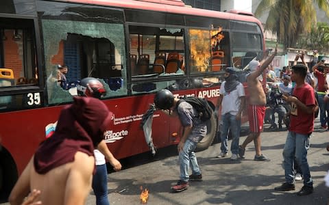 Demonstrators destroying a city bus in Urena - Credit: AP