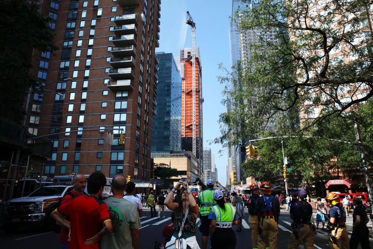 Bystanders watch as firefighters try to put out a crane fire in New York City on Wednesday morning.