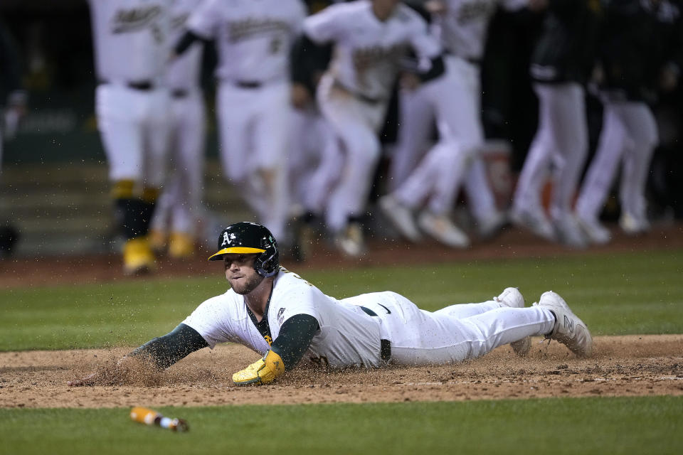 Oakland Athletics' Max Schuemann slides, scoring the winning run on a single by Lawrence Butler during the 10th inning of the team's baseball game against the Washington Nationals in Oakland, Calif., Friday, April 12, 2024. (AP Photo/Tony Avelar)