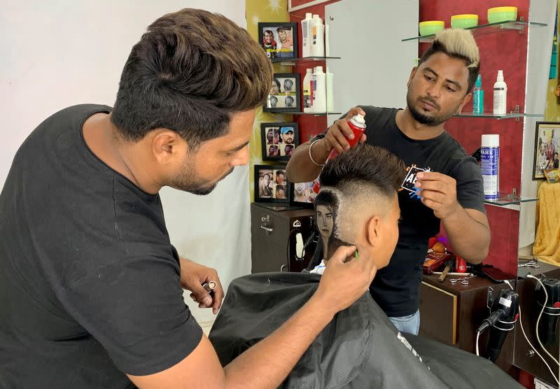 Barber brothers Rajwinder Singh Sidhu and Gurwinder Singh Sidhu make a haircut tattoo of Michael Jackson in a customer's hair, in Dabwali