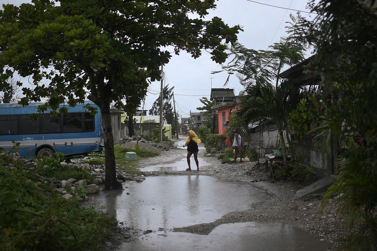 A resident crosses a flooded street the morning after Tropical Storm Grace swept over Trou Mahot, Haiti, Tuesday, Aug. 17, 2021, three days after a 7.2-magnitude earthquake.