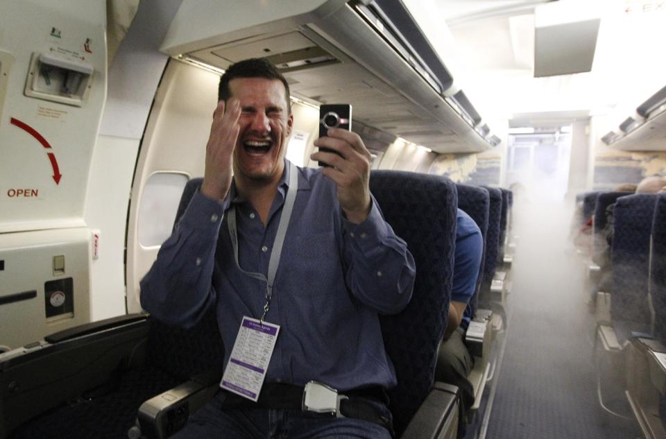 In this photo made Thursday, Jan. 26, 2012, Eric Mueller of Los Angeles, Ca., laughs and films for his blog as a cabin fills with smoke during a simulator emergency exercise at the American Airlines training facility in Fort Worth, Texas. It’s the ultimate field trip for aviation geeks, 160 of frequent fliers chartered an American Airlines jet and hoped across the country visiting aviation themed spots. (AP Photo/LM Otero)