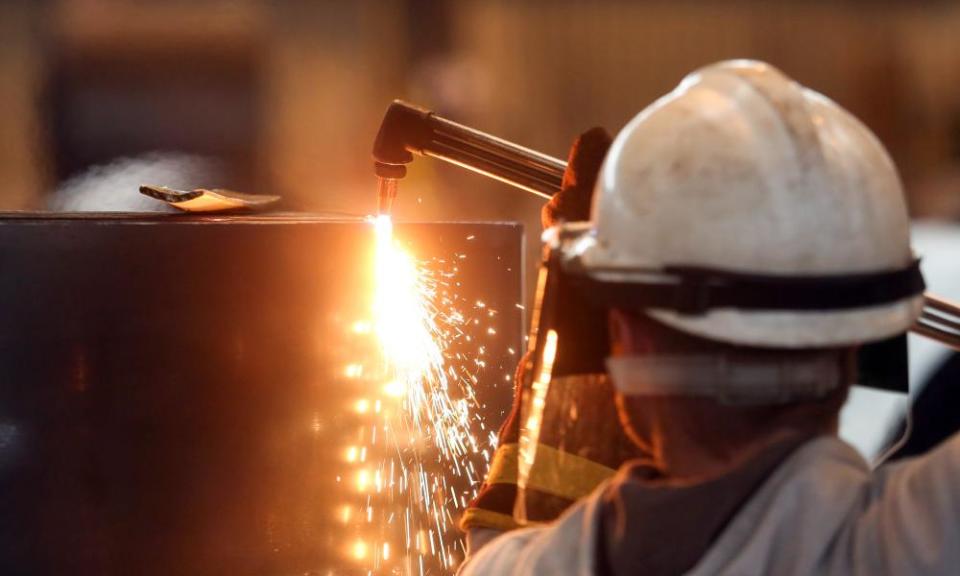 An employee cuts a sample from a roll of coiled steel