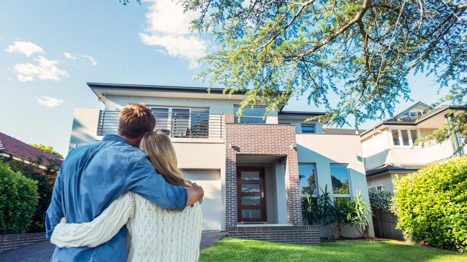 Couple standing in front of their new home.