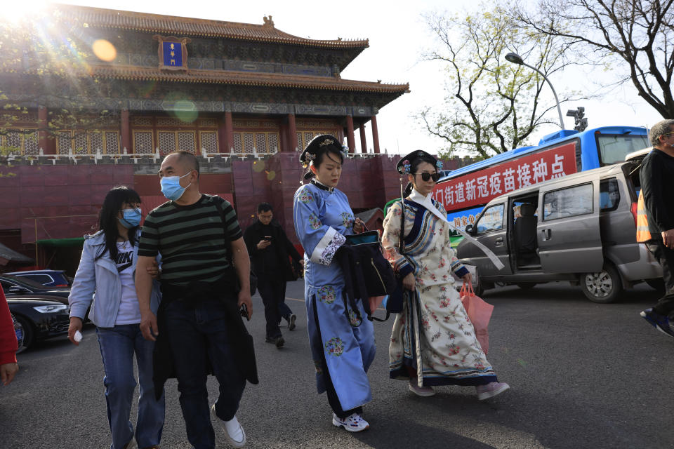 Residents in traditional costumes leave from a side entrance to the Forbidden City where a bus offers free coronavirus vaccinations in Beijing on Wednesday, April 14, 2021. China's success at controlling the outbreak has resulted in a population that has seemed almost reluctant to get vaccinated. Now, it is accelerating its inoculation campaign by offering incentives — free eggs, store coupons and discounts on groceries and merchandise — to those getting a shot. ​(AP Photo/Ng Han Guan) hoto/Ng Han Guan)