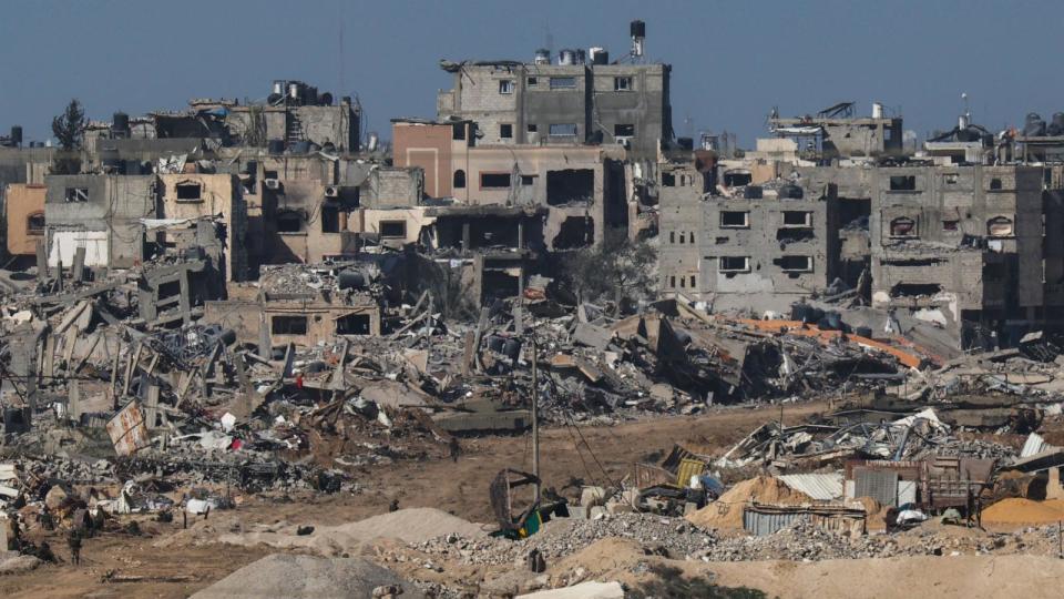 PHOTO: A picture taken from southern Israel bordering the Gaza Strip on Dec. 22, 2023, shows an Israeli army tank rolling past debris of buildings in the Gaza Strip amid ongoing battles with the Hamas militant group.   (Jack Guez/AFP via Getty Images)