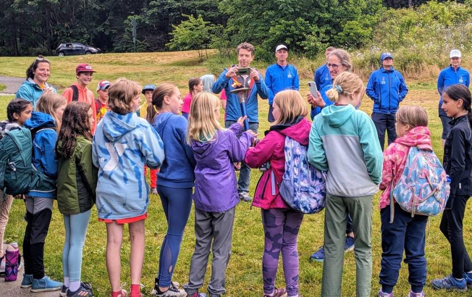 Caption: Girl on the Run members passing the peace torch around at Lake Padden in Bellingham. on June 27, 2024.