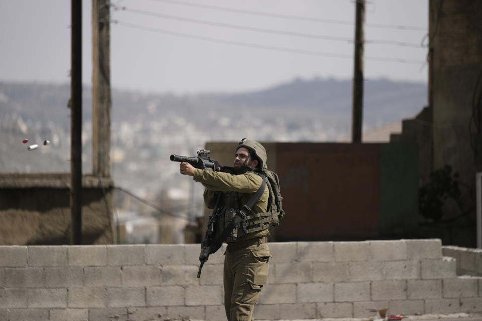 An Israeli soldier fires tear gas at Palestinians during clashes after Israeli settlers attacked Palestinians in Huwara, near the West Bank town of Nablus, Thursday, Oct. 13, 2022. (AP Photo/ Majdi Mohammed)