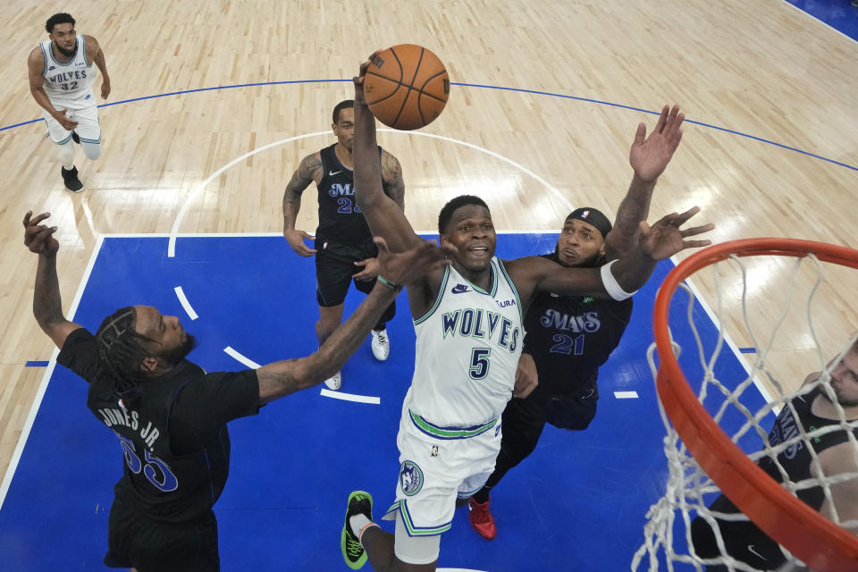 El base de los Timberwolves de Minnesota Anthony Edwards salta con el balón para anotar frente a Derrick Jones Jr. y Daniel Gafford de los Mavericks de Dallas en el juego 2 de las finales de la Conferencia Oeste el viernes 24 de mayo del 2024. (AP Foto/Abbie Parr)