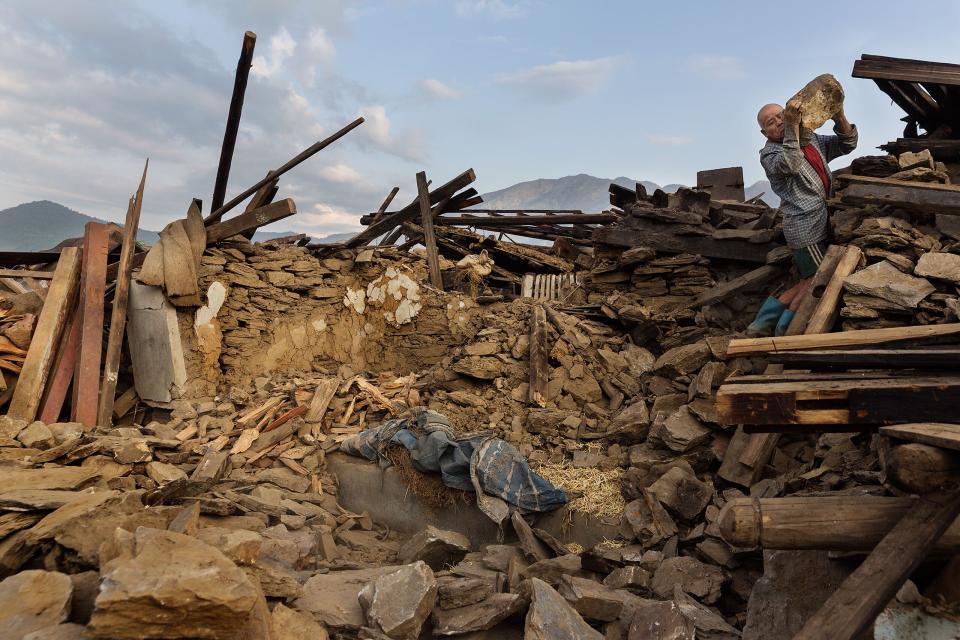 Nepal earthquake. Barpak, the epicenter of the earthquake. Funeral of Pur Bahadur Gurung, 26, who had just been dug out of the rubble. Saainli Gurung, his mother weeping. Scenes of villagers salvaging building materials and personal possessions. Dhan Raj Ghale, 30, dressed in mourning garb after the death of his wite, salvaging buildings materials and possessions from his house. by James Nachtwey