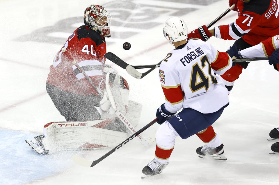 New Jersey Devils goaltender Akira Schmid (40) makes save in front of Florida Panthers defenseman Gustav Forsling (42) during the third period of an NHL hockey game, Tuesday, March 5, 2024, in Newark, N.J. The Florida Panthers won 5-3. (AP Photo/Noah K. Murray)