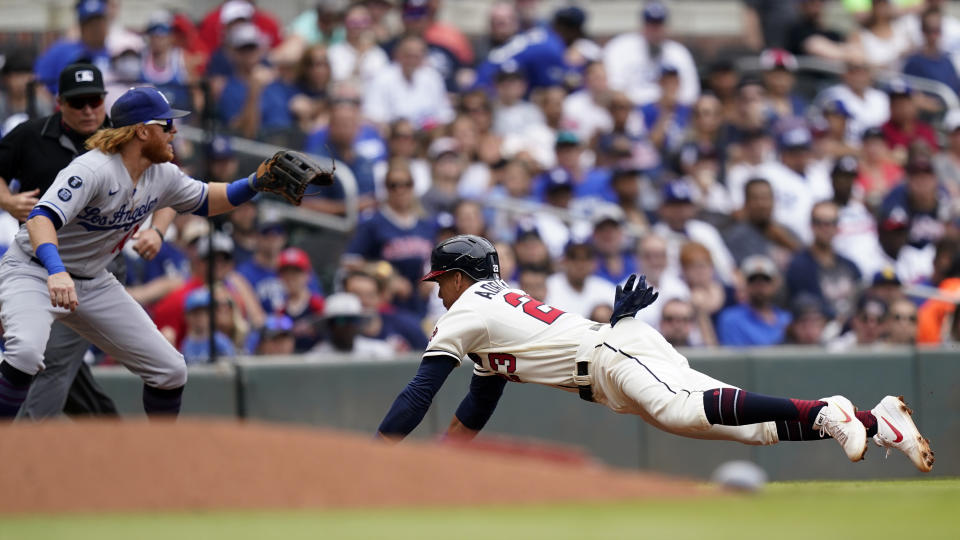 Atlanta Braves' Ehire Adrianza, right,slides into third base ahead of the throw to Los Angeles Dodgers third baseman Justin Turner, front left, after a ground ball by William Contreras in the fourth inning of a baseball game Sunday, June 6, 2021, in Atlanta. (AP Photo/Brynn Anderson)