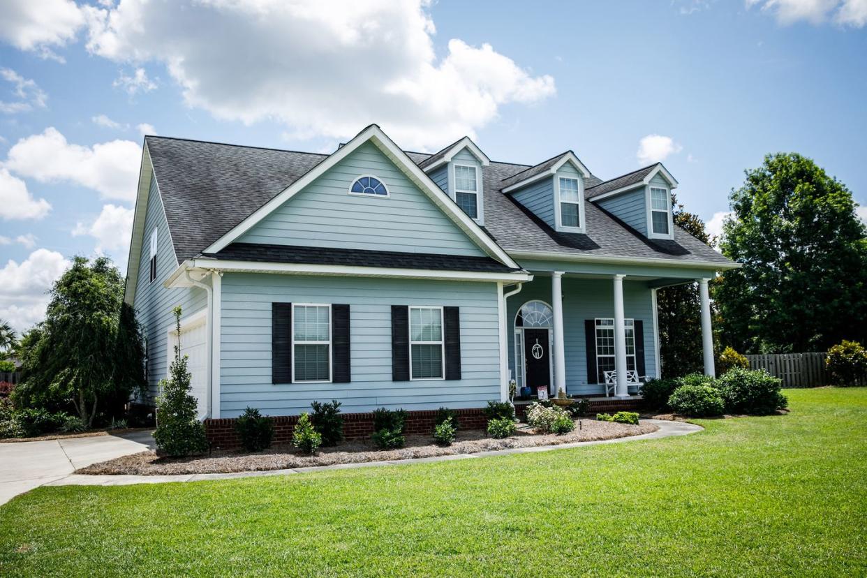 front view of blue house with siding in the suburbs