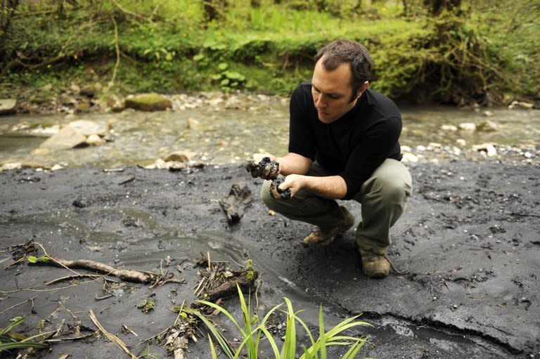 Suren Gazaryan looks at a black substance close to the Sochi 2014 Winter Olympics site. He says the substance is a mudslide from an illegal dump