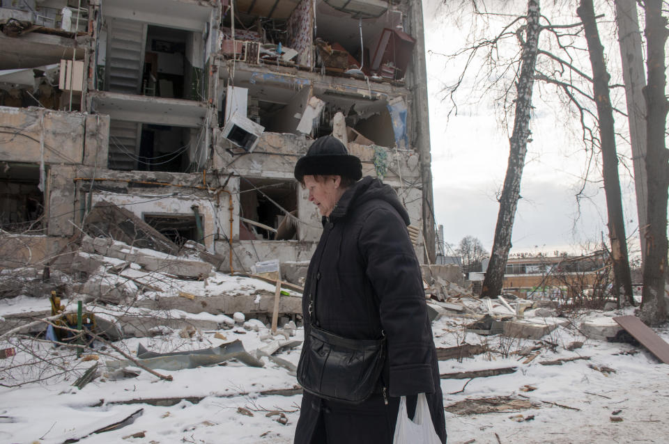 A woman walks past building damaged by shelling, in Kharkiv, Ukraine, Sunday, March 13, 2022. (AP Photo/Andrew Marienko)