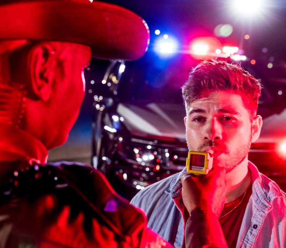 A police officer administers a blood alcohol level test.