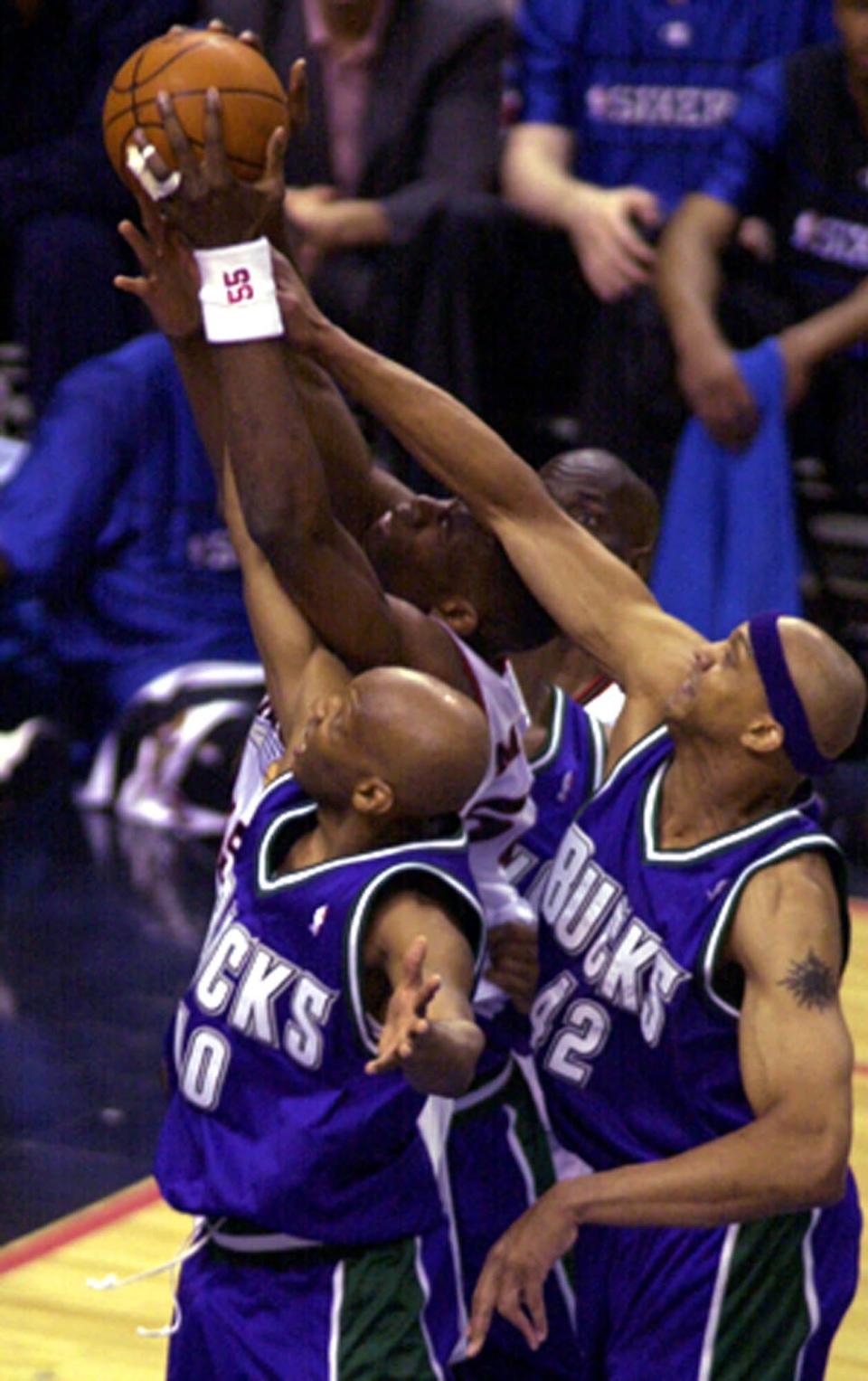 Philadelphia 76ers' Dikembe Mutombo fights for a rebound with Milwaukee Bucks' Sam Cassell (10) and Scott Williams (42) during the first half of game one of the Eastern Conference finals on May 22, 2001, in Philadelphia.