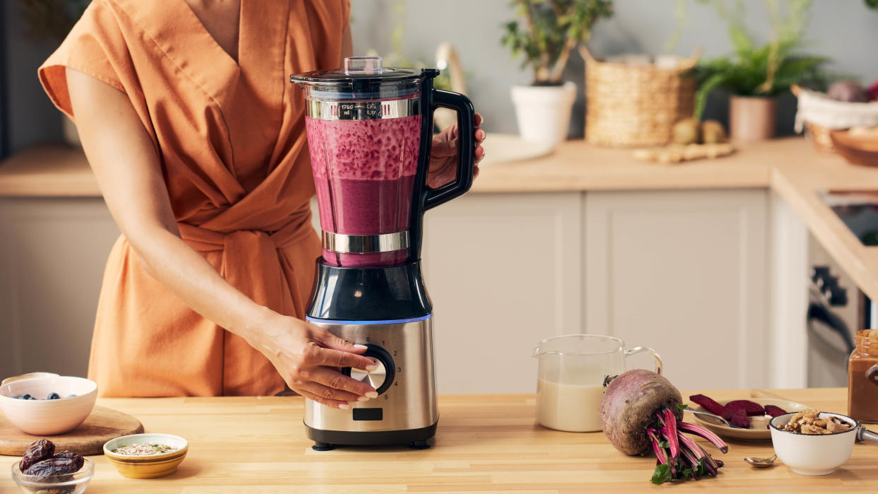  A blender filled with beetroots being run in a kitchen  