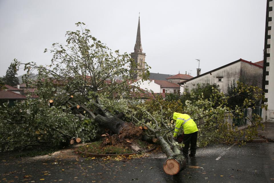 A man saws a tree that fell on a parking lot on Nov. 2, 2023, in Hasparren, southwestern France.