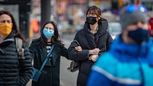 Pedestrians wear masks while walking along a busy street in downtown Ottawa on March 16. (Brian Morris/CBC - image credit)