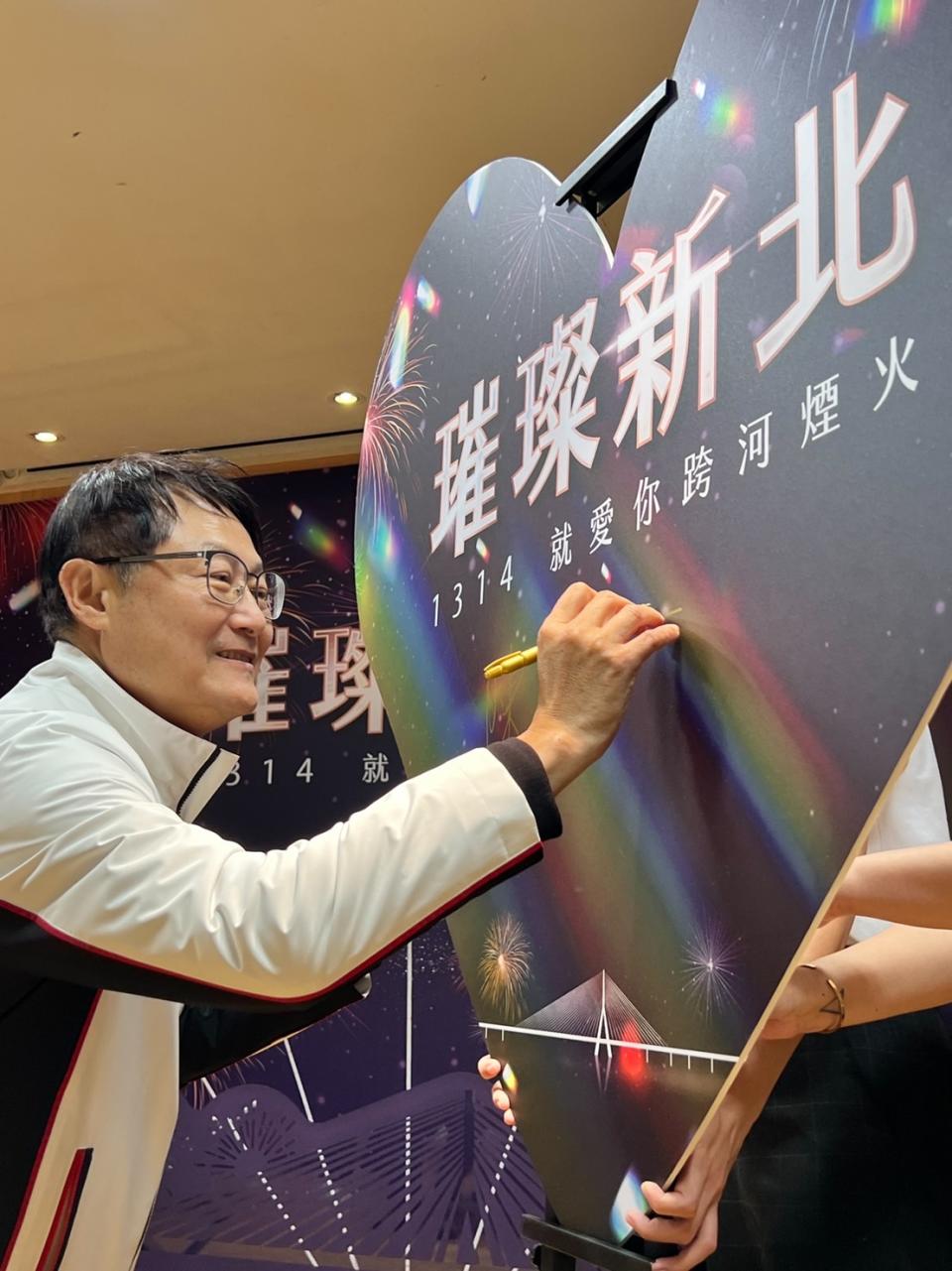 陳純敬在愛心造型板簽名，為今年跨河煙火揭幕。   圖：新北市高灘處提供