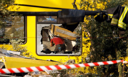 A firefighter works at the site where two passenger trains collided in the middle of an olive grove in the southern village of Corato, near Bari, Italy, July 12, 2016. REUTERS/Alessandro Garofalo