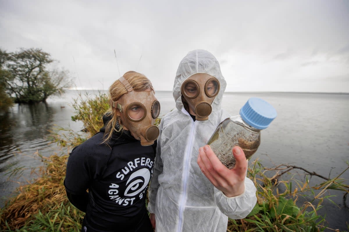 Carla Magee (left) and Aine McAuley from  Surfers Against Sewage (SAS) protest against pollution at Lough Neagh in Northern Ireland, which has been polluted by deadly blue-green algae (PA)
