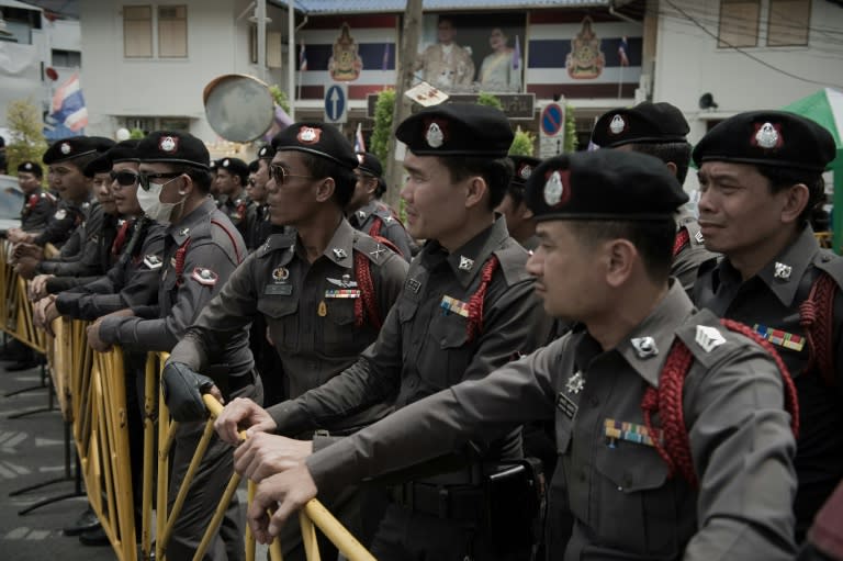 Policemen look on as supporters of arrested anti-coup activists gather outside a police station in Bangkok on June 24, 2015