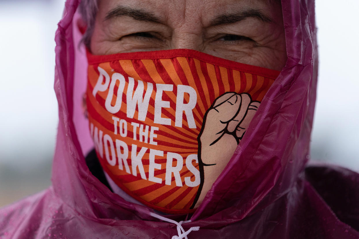 Image: A demonstrator's mask reads 