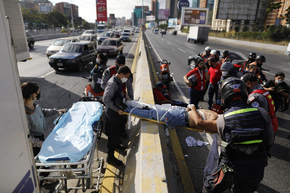 Angels of the Road volunteer paramedics move a person injured in a motorcycle accident on a scoop stretcher into their single ambulance, in Caracas, Venezuela, Wednesday, Feb. 10, 2021. The volunteer paramedics say they feed off the adrenaline of each emergency call. (AP Photo/Ariana Cubillos)