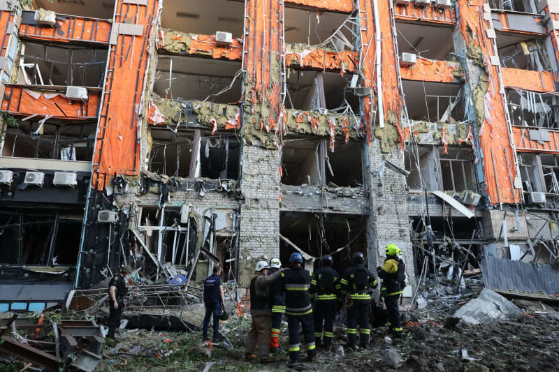 Rescue workers stand in front of an office building that was destroyed by a Russian missile attack in the center of Kharkiv in northeastern Ukraine. -/Ukrinform/dpa