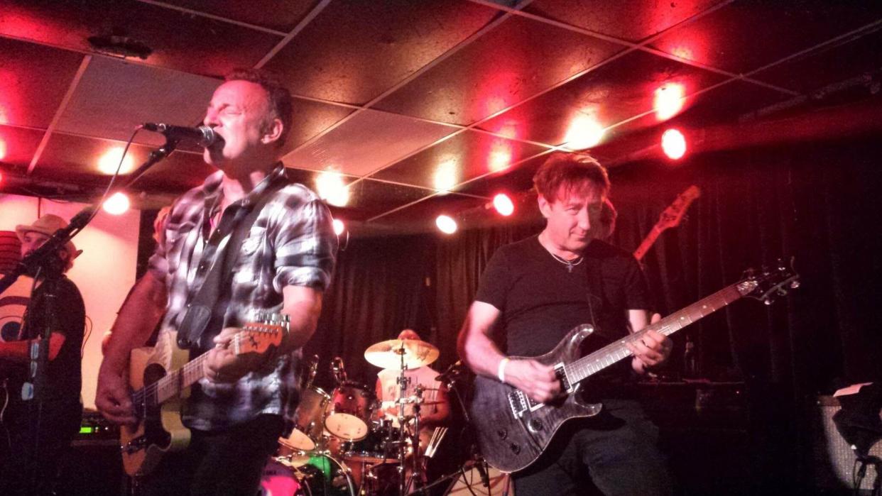 Joe Grushecky and The Houserockers' Danny Gochnour (right) hoists his favorite guitar while backing New Jersey rocker Bruce Springsteen in this action shot.