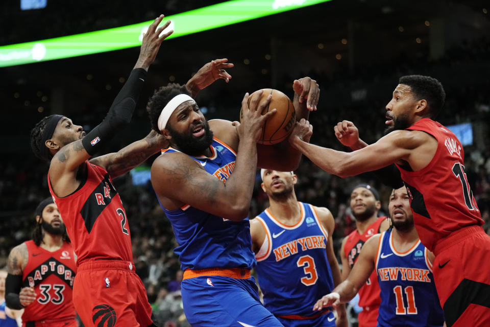 New York Knicks center Mitchell Robinson, center, is fouled by Toronto Raptors forward Garrett Temple, right, as Raptors forward Jalen McDaniels (2) defends during the second half of an NBA basketball game Wednesday, March 27, 2024, in Toronto. (Frank Gunn/The Canadian Press via AP)